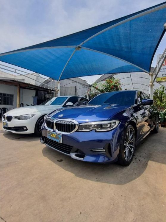 BMW Série 3 azul finalizada na área coberta da loja